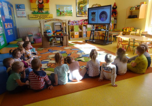 Dzieci oglądają prezentację multimedialną o pracy stomatologa.